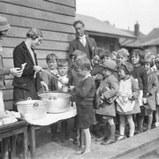 Schoolchildren line up for free issue of soup and a slice of bread during the Depression