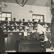 A class of boys watching a training demonstration by a butcher, with Father Thomas Dunlea standing to the left, Boys' Town Engadine, New South Wales, 1954
